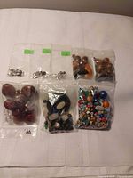 Overview of eight plastic bags containing findings and assorted beads