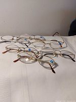 Six pairs gold metal reading glasses laid on white surface