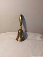 Full view of brass hand bell standing upright