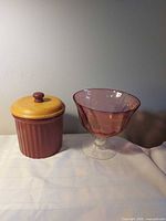 Pottery canister with wood lid beside amethyst pedestal bowl