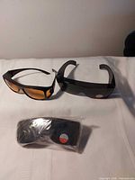 Three pairs of wraparound sunglasses, two unwrapped, one sealed
