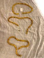 Three yellow bead strands laid out on cloth