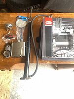 All seven bicycle accessories laid out: pump, flask, compass clip, bell, mirror, LED lights and boxed rack bag