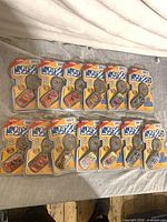 Thirteen BLING dog tag keychains in original blister packaging laid out on table