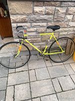 Full side view of yellow CCM road bike against stone wall