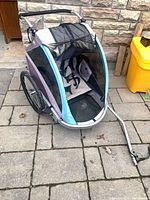 Front three-quarter view of blue/teal double bike trailer with tow arm attached