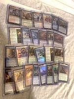 Array of sleeved and toploaded foil rares spread on cloth surface