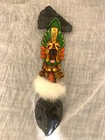 Full view of decorative dagger axe, showing obsidian axe head, carved painted handle, fur accent and obsidian dagger blade