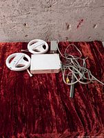 Group shot of two Wii steering wheels with remotes, one Wii console, sensor bar, power adapter and cables