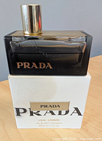 Front view of bottle on top of box showing Prada logo and cap