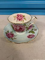 Teacup on saucer showing rose pattern and gold trim
