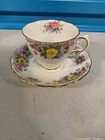 Front angled view of teacup on saucer showing floral pattern and gold trim