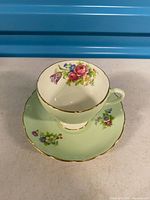 Teacup on saucer front view showing floral design and gold trim