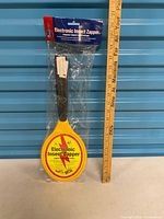 Full view of sealed electronic insect zapper racket beside ruler for scale