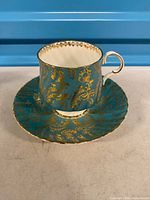 Teacup on saucer, showing turquoise and gold design
