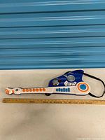 Full view of toy guitar showing size against ruler