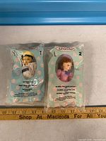 Front view of both sealed dolls showing packaging and characters