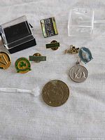 Assorted pins, medals, coin, display boxes on cloth background