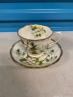 Side view of teacup on saucer showing pattern and gold trim wear