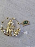 Clown brooch and turtle pendant side by side on fabric background