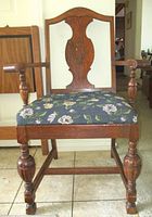 Front view of tiger oak armchair showing carved back splat, turned arms and legs, floral upholstered seat