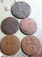 Five British pennies laid out showing varying wear