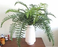 Full view of artificial Boston fern in vase on table