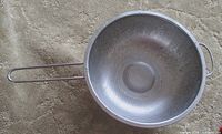 Top view of stainless steel colander showing perforations and handles