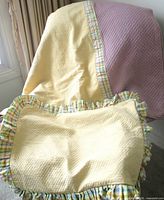 Bedspread draped over chair with matching sham and throw pillow visible