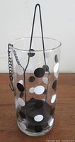 Full view of cylindrical polka dot glass candle holder with iron hanger inside