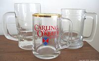 Front view of three beer mugs showing Carling O'Keefe logo and plain mugs