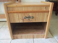 Front view of wood side table showing drawer with brass pull and open shelf