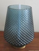 Front view of teal diamond-pattern glass candle holder on brass base