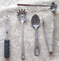 Five stainless steel kitchen utensils laid out on carpet