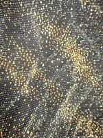 Close-up of metallic gold and silver speckled pattern on black fabric
