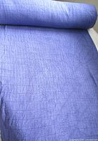 Full roll of blue/mauve knit fabric showing width and texture