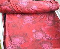 Rolled bolt of red fabric with pink roses