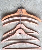Stack of five vintage wooden advertising hangers showing overall styles and logos