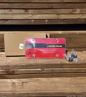 front view of clear license plate frame set in front of box