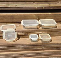 All six Pampered Chef glass containers with lids arranged on steps