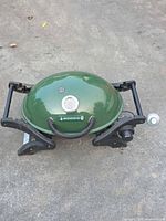 Closed grill showing green lid with temperature gauge and folding supports