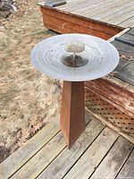 Full view of rusted metal pedestal bird bath with stainless basin and stone accent
