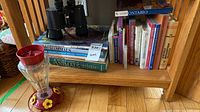Binoculars, hummingbird feeder and books on shelf