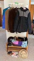 Overall view of jackets on rack, shelf with hats, scarves, basket and accessories