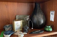 Shelf view showing all decor objects including geode, stones, clock, plaque, kinetic sculpture, vase, creamer