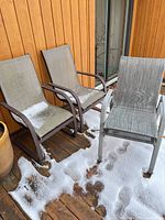 Three patio chairs on deck, snow on seats