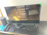 Front view of TCL Roku TV with speakers, remotes and cables visible