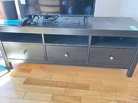 Front view of dark brown TV console table showing three drawers and three open cubbies