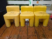 Front view of three yellow Little Tikes children's chairs showing overall style and wear