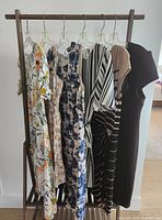Front view of six dresses on wooden rack